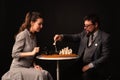 A man with a girl plays chess and smokes a pipe on a dark background