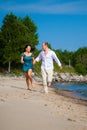 Man and girl running along coast of blue sea Royalty Free Stock Photo