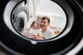 Man and girl view from washing machine inside. Father with daughter does laundry daily routine Royalty Free Stock Photo