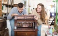 Man with girlfriend admiring vintage wooden bureau