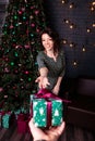 Man gives a young woman a Christmas present. Beautiful girl in a decorated room Royalty Free Stock Photo