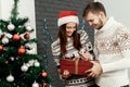 man giving big present to his woman. happy stylish family smiling at decorated christmas tree. joyful cozy moments in winter Royalty Free Stock Photo