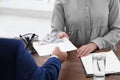 Man giving bribe money to woman at table