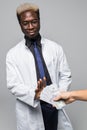 Man giving bribe to a afro american doctor refusing the money, isolated on gray background Royalty Free Stock Photo