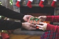 Man giving Christmas and New Year Gift box to woman in front of christmas tree, fireplace with flame. Xmas concept. Royalty Free Stock Photo