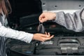 Man giving client keys to her repaired car in auto repair service Royalty Free Stock Photo