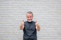 Man giving a double thumbs up gesture in front of a white brick wall Royalty Free Stock Photo