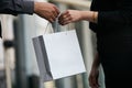 Man giving gift in paper bag to woman, close-up Royalty Free Stock Photo