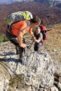 Man giving helping hand to friend to climb mountain rock cliff. Royalty Free Stock Photo