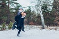 Man giving his girlfriend piggyback in winter forest. Couple in love having fun outdoors. Winter activities Royalty Free Stock Photo