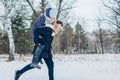 Man giving his girlfriend piggyback in winter forest. Couple in love having fun outdoors. Winter activities Royalty Free Stock Photo