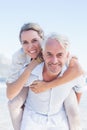 Man giving his smiling wife a piggy back at the beach Royalty Free Stock Photo