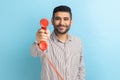 Man giving phone handset looking at camera, smiling looking friendly joyful, helpful contact center. Royalty Free Stock Photo