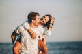 Man giving piggyback ride to girlfriend on beach