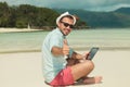 Man giving thumbs up while sitting on the beach with ipad Royalty Free Stock Photo