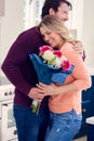 Man Giving Woman Bunch Of Flowers To Celebrate On Anniversary Or Birthday In Kitchen At Home