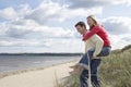 Man giving woman piggy back on dunes