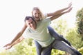 Man giving woman piggyback ride outdoors smiling Royalty Free Stock Photo