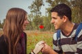 Man giving a woman single red anemone flower in anemones field Royalty Free Stock Photo