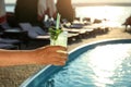 Man with glass of fresh summer cocktail near swimming pool outdoors at sunset. Space for text Royalty Free Stock Photo
