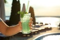 Man with glass of fresh summer cocktail near swimming pool outdoors at sunset. Space for text Royalty Free Stock Photo