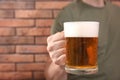 Man with glass of tasty beer near red brick wall, closeup. Space for text Royalty Free Stock Photo