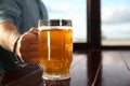 Man with glass of tasty beer at wooden table in pub, closeup. Space for text Royalty Free Stock Photo