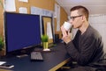 A man with glasses drinks coffee, tea and looks at the green screen. A man works at home. Stay home, freelancer, training