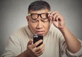 Man with glasses having trouble seeing phone screen vision problems Royalty Free Stock Photo