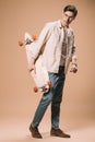 Man in glasses holding wooden skateboard while standing