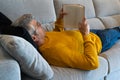 Man with glasses lying on the sofa reading a book. Relaxing at home Royalty Free Stock Photo