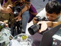 A man with glasses and other photographers bring their cameras into focus on a piece of moss