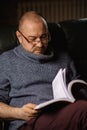 A man with glasses is reading a book. Middle-aged man of ordinary appearance in casual clothes at home. Reading, learning Royalty Free Stock Photo