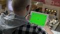 A man in glasses sits with a tablet, on the screen of which chromakey with markers