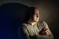Man with glasses sitting in the dark room Royalty Free Stock Photo