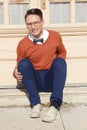 Man with glasses and sweater sitting on steps in front of house Royalty Free Stock Photo