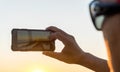 Man with glasses taking photo with mobile phone, sunset light Royalty Free Stock Photo