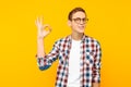 Man in glasses, white t-shirt and shirt, showing the gesture is good, good, on a yellow background