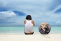 Man with globe sitting on beach Royalty Free Stock Photo
