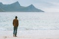 Man globetrotter walking on Haukland beach in Norway Lofoten islands adventure travel lifestyle