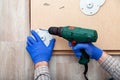 Man in gloves assembles table furniture with drill. Assembly, furniture repair home master. Male hand with drill on floor. Top Royalty Free Stock Photo