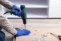 Man in gloves assembles table furniture with drill. Assembly, furniture repair home master. Male hand with drill on floor. Copy Royalty Free Stock Photo