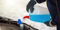 Man with gloves pouring antifreeze coolant into car reservoir in winter season. Royalty Free Stock Photo