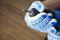 Man in gloves preparing a screwdriver for repair works at home.Closeup shot with empty space Male hand in blue gloves holdin