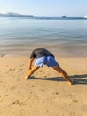 A man goes in for sports, does exercises on the seashore