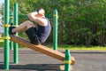 Man goes in for sports in the open air, on a special platform, does an exercise on a press, close-up