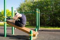 A man goes in for sports outdoors, on a special platform, does an exercise on a press