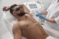 Man with goggles and bare chest undergoes procedure of arm pit laser epilation in clinic Royalty Free Stock Photo