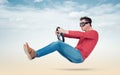 Man in goggles drives a car with a steering wheel on background of clouds
