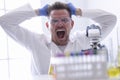 Man in goggles and rubber gloves pulls out hair on his head in chemical laboratory portrait Royalty Free Stock Photo